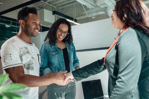 Smiling couple shaking hands with advisor in modern office.