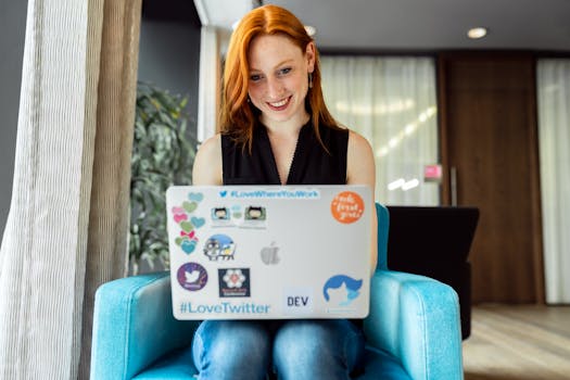 Smiling woman engaged in remote work on a laptop at home office setting.