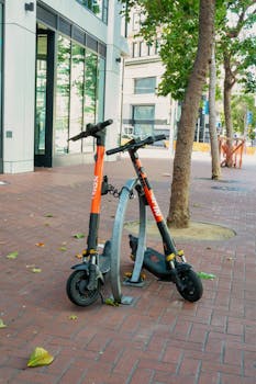 Two electric scooters parked securely on a sunny street in San Francisco, California.